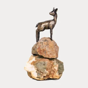 Bronze Klipspringer sculpture standing gracefully atop stacked natural rocks, symbolizing agility and balance.